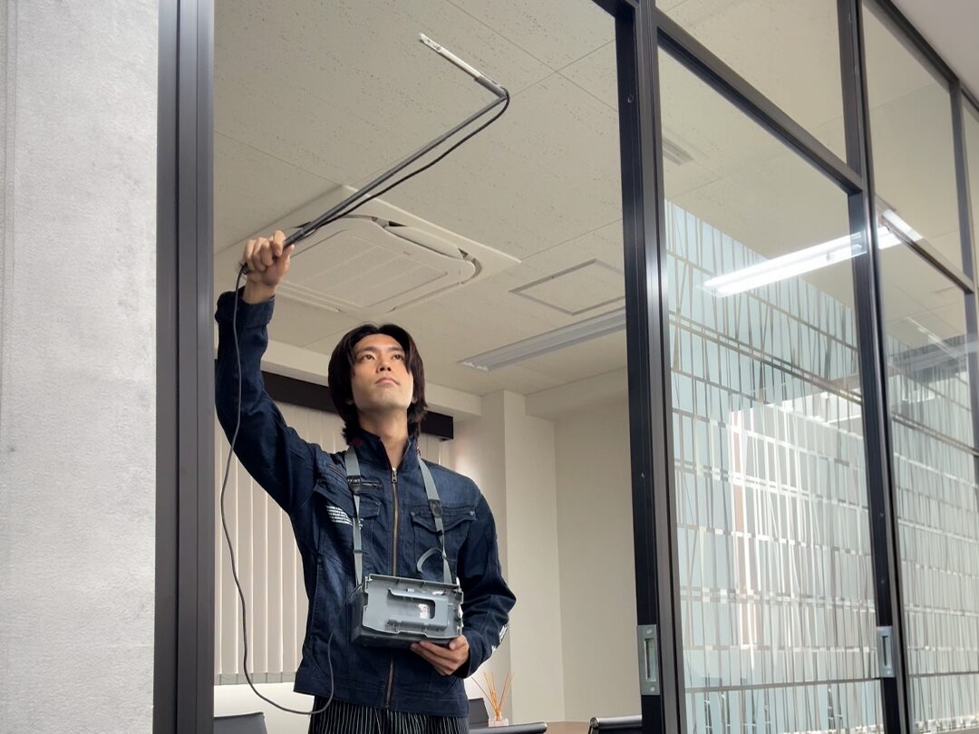 オフィスの出入口で風速計を使った測定動作を再現している様子
